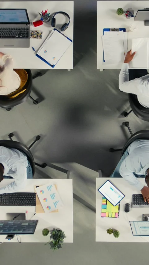 Vertical Video Top down view zoom in of diverse work team study analytics and Stock Footage 321780662