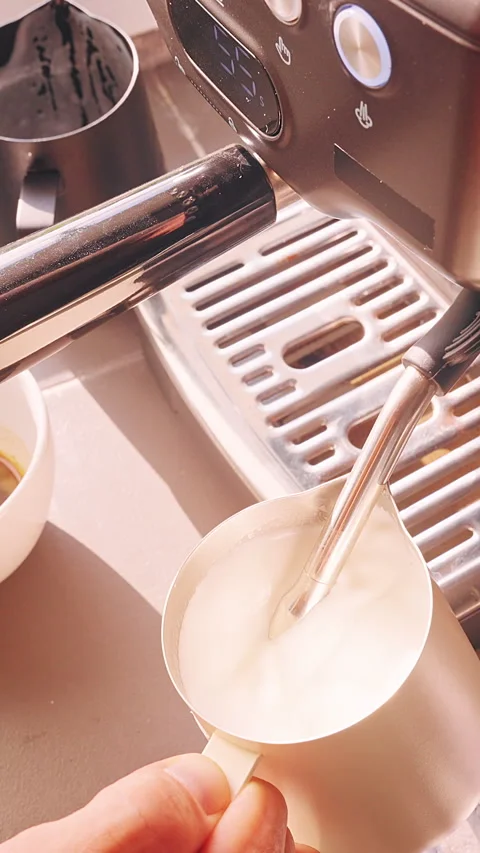 Vertical video. Top Down View Frothing Milk With Steam Wand In Metal Pitcher Bes Stock Footage 331024038