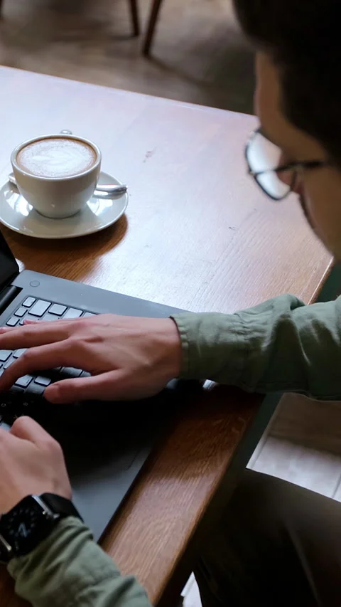 Vertical video. Top view of man in casual clothes is typing on a laptop Stock Footage 345236584