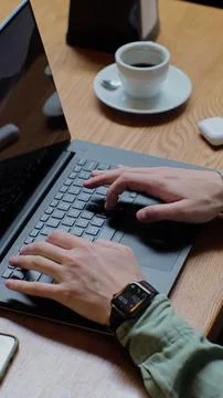 Vertical video. Top view of man in casual clothes is typing on a laptop, si.. Stock Photos