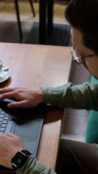 Vertical video. Top view of man in casual clothes is typing on a laptop, si.. Stock Photos