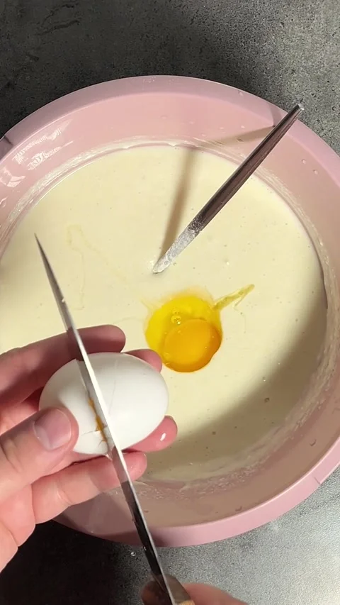 Vertical video. Top view. Yellow yolk in dough in pink bowl Stock Footage 298658156