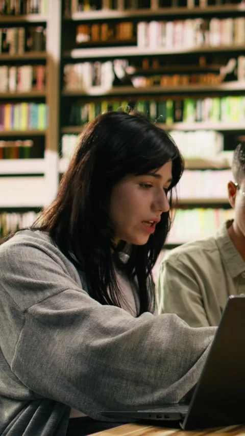 Vertical Video Tutor pointing toward laptop and explaining coursework to student Stock Footage 336379270