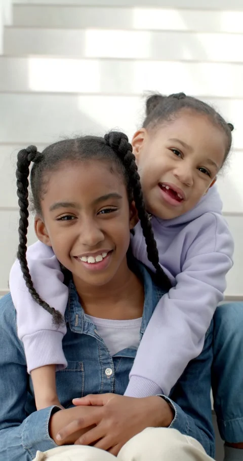 Vertical video: Two African female children sitting on steps smaller climbing Stock Footage 346712573