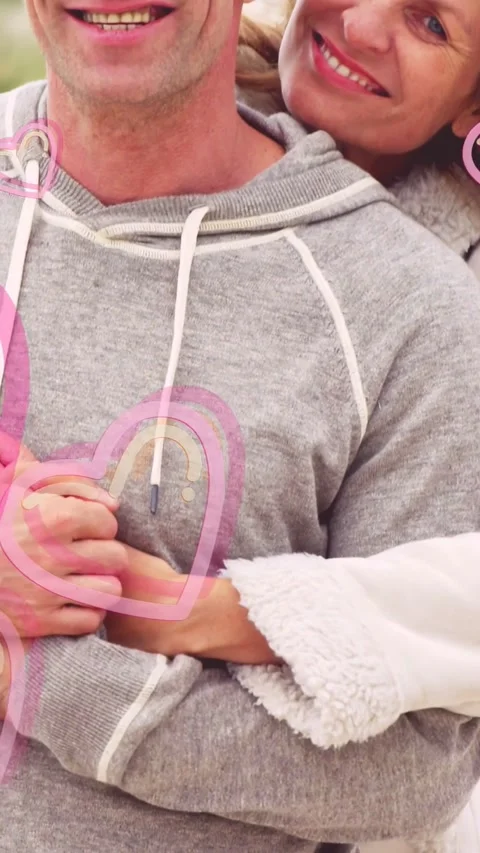 Vertical video: Two clasping hands while hugging, pink hearts popping, cam Video stock 333577026