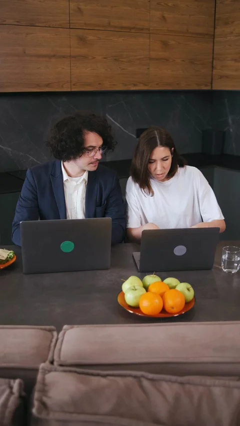 Vertical video Two colleagues, husband and wife, work on laptops in a modern Stock Footage 296824849