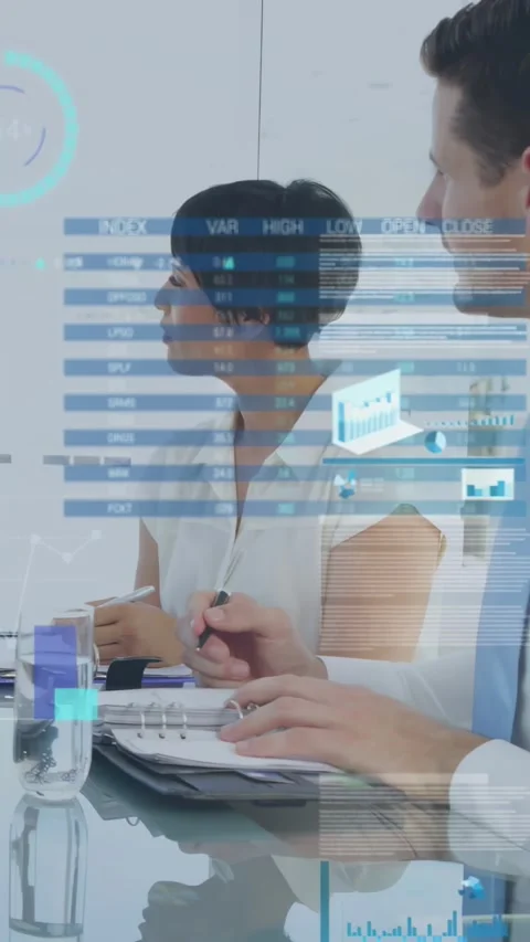 Vertical video: Two coworkers watching index charts updating and noting data for Stock Footage 331405016