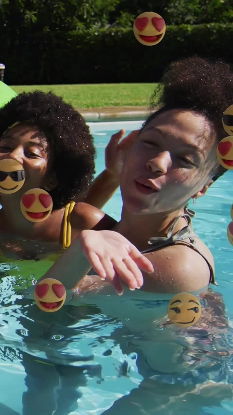 Vertical video: Two friends posing in pool, right woman blowing kiss causing Stock Footage 331077483