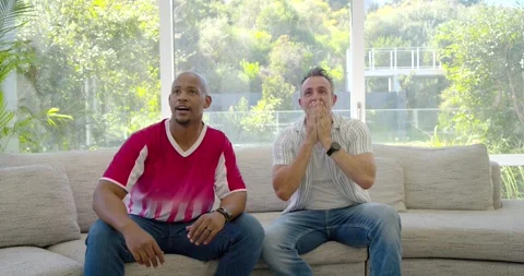 Vertical video: Two friends watching big play on TV, men standing, cheering as Stock Footage 339592163