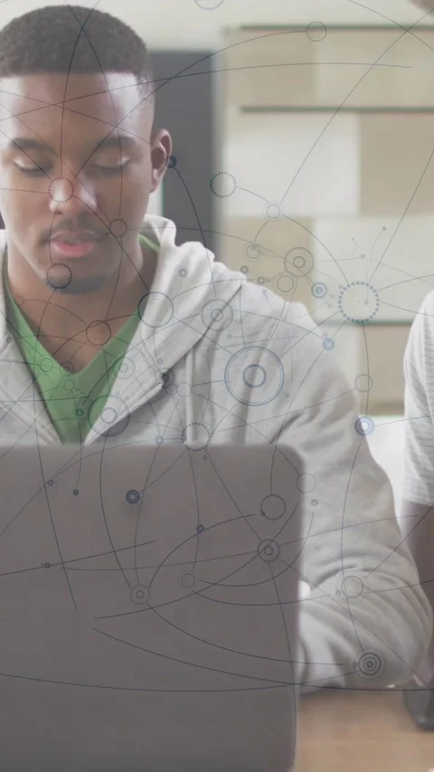 Vertical video: Two men at desk one man pointing causing data map across laptop Stock Footage 334544725