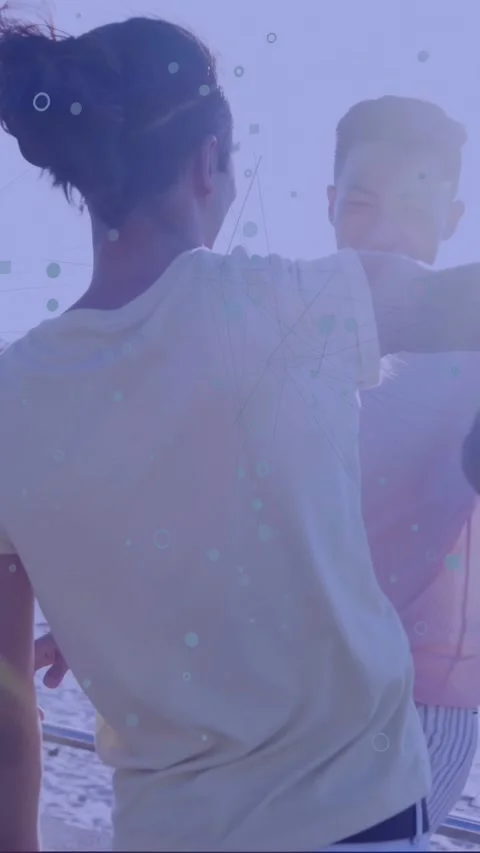 Vertical video: Two men hand spinning into hug at railing, shapes overlaying, Stock Footage 334128229