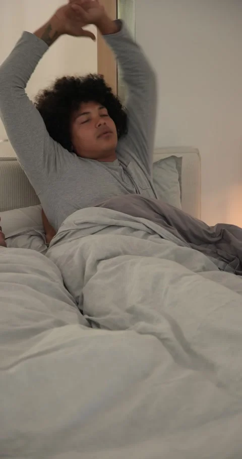 Vertical video: Two men reacting to alarm clock ringing, turning off, cuddling Stock Footage 345217127