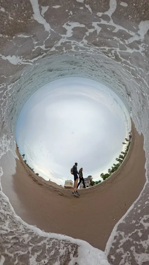Vertical video. Two people stroll by the edge of the water, captured with a Tiny Video stock 293111088