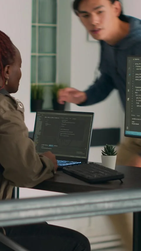 Vertical video: Two software coders analyzing source code on computer and laptop Stock Footage 218575309