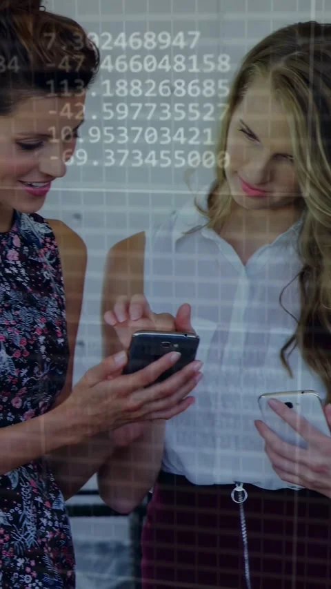 Vertical video: Two tech pros comparing phones as one tapping phone showing Stock Footage 332775788