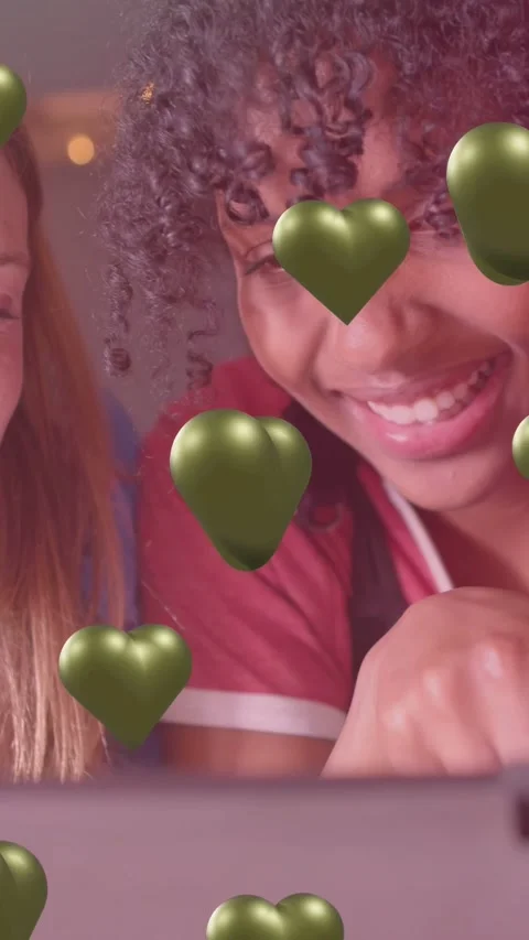 Vertical video: Two teens leaning over device, tapping and shifting green AR Stockbeeldmateriaal 334378821