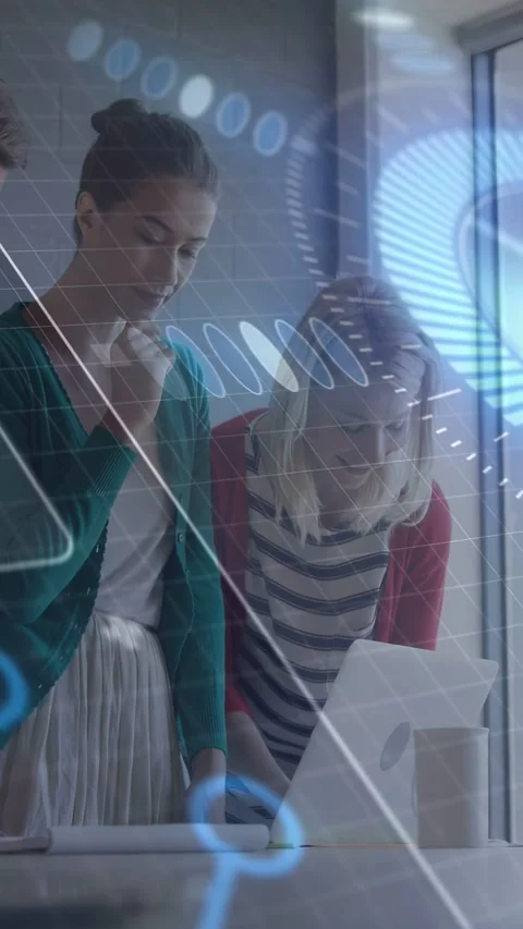 Vertical video: Two women leaning over PC holding doc making HUD graphs for tech Stock Footage 332806610