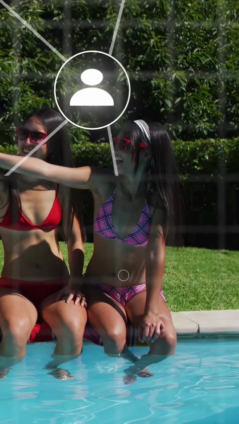 Vertical video: Two women at pool edge, left raising arm posing selfie, tech Stock Footage 340133448