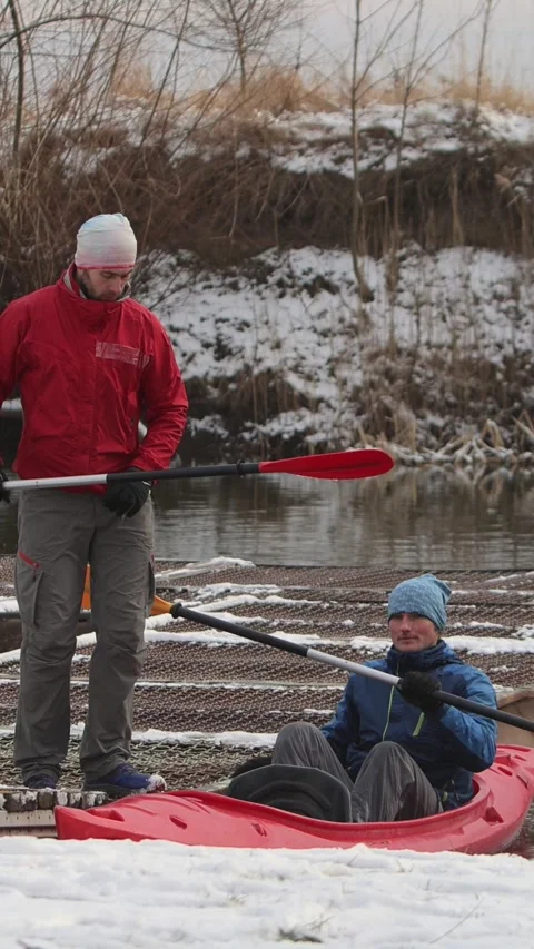Vertical video. Two young men of athletic build sit in a red kayak. Winter scene Video stock 301552831