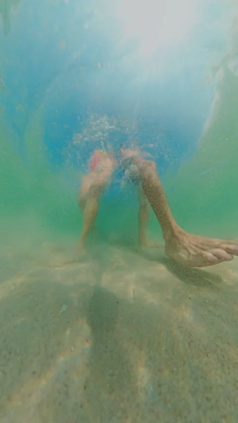 Vertical video. Underwater Low Angle View Couple Walking On Sandy Bottom With St Stock Footage 333265211