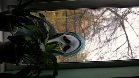 Vertical video an unknown person appears outside the window wearing a screaming Stock Footage 163778503