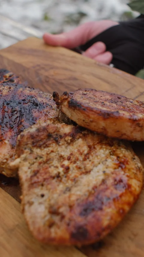 Vertical video of unknown young man holding beef steak just cooked on bonfire Stock Footage 297945040