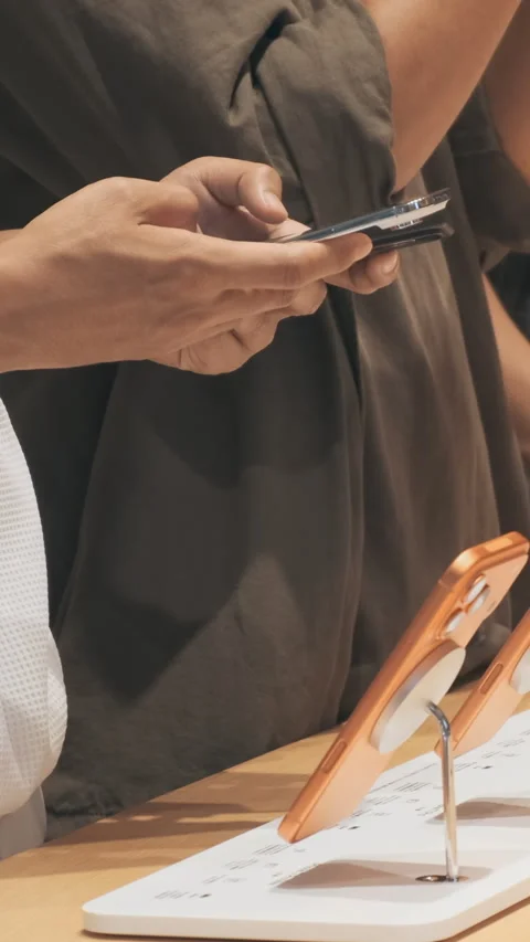 Vertical video: Unrecognizable customers test iPhone 17 lineup at Apple Store Stock Footage 322514677