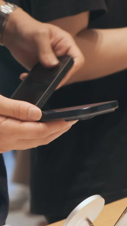 Vertical video: Unrecognizable man approaches stand with iPhone17 smartphones Stock Footage 322516030