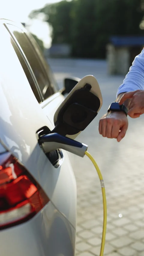 Vertical Video of unrecognizable man plugging in charging cable to to electric Stock Footage 306094041
