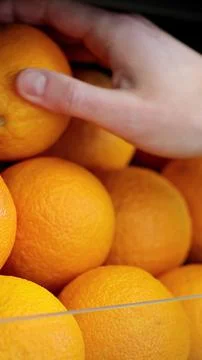 Vertical video. Unrecognizable man standing in supermarket and choosing oranges. Fotos de archivo