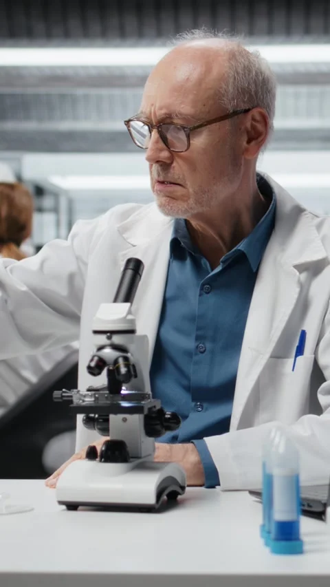 Vertical video Upbeat elderly lab professional investigating blue liquid polymer Stock Footage 327098212