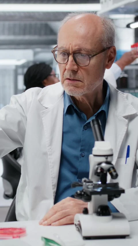 Vertical video Upbeat elderly lab professional investigating blue liquid polymer Stock Footage 327333894