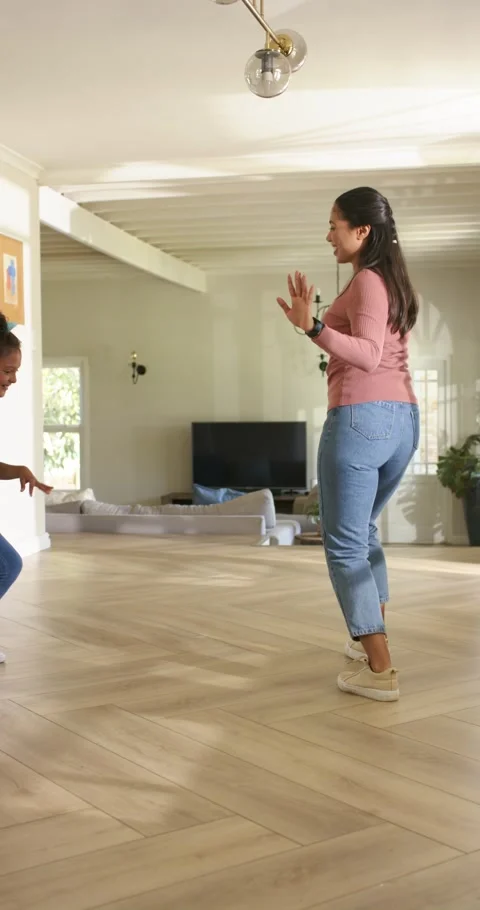Vertical video: Upon girl touching floor mom mimicking and dancing on floor in Stock Footage 345320875