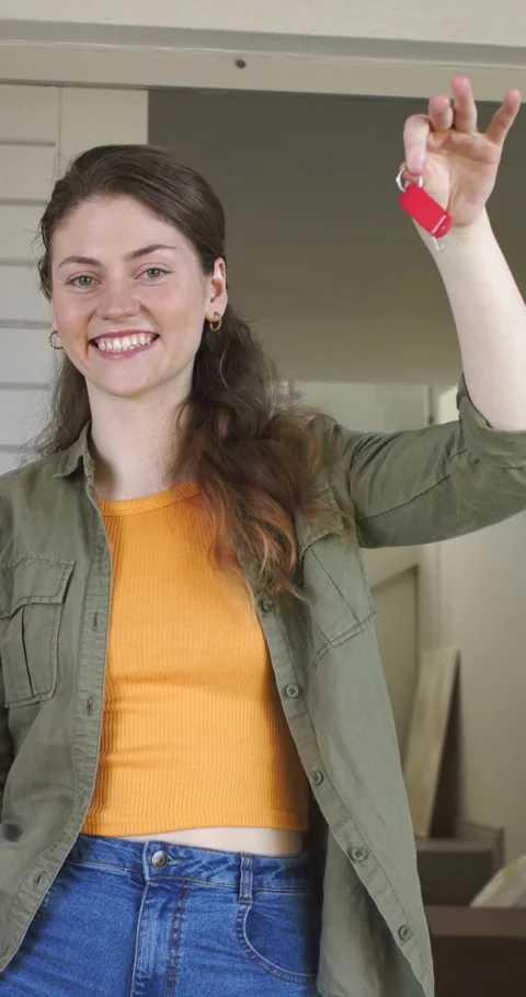 Vertical video: Upon unlocking door woman smiling while holding red key fob at Stock Footage 345217912