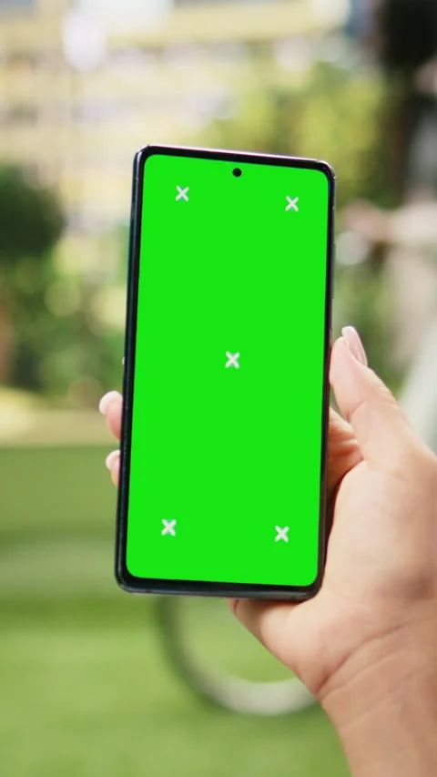 Vertical Video Vertical chroma key screen on mobile phone held against blurred Stock Footage 344383919