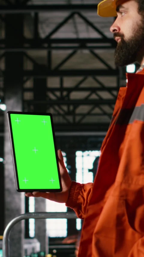 Vertical Video Vertical green screen on tablet held by male engineer in heavy Stock Footage 330375539