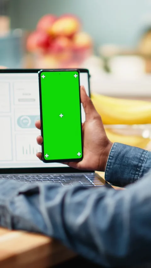 Vertical Video Vertical green screen on mobile phone near laptop with analytics Stock Footage 344531223