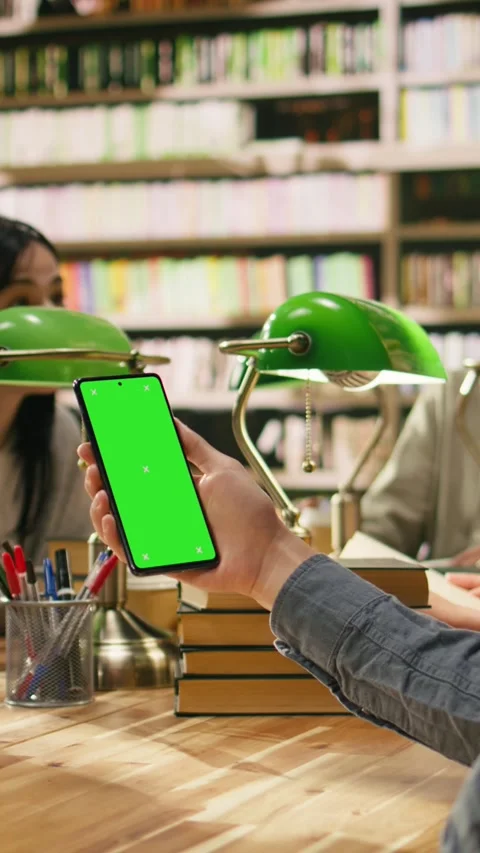 Vertical Video Vertical isolated green screen on smartphone held over wooden Stock Footage 336379879