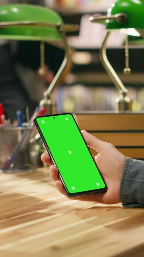 Vertical Video Vertical isolated green screen on smartphone held over wooden Stock Footage 336380770