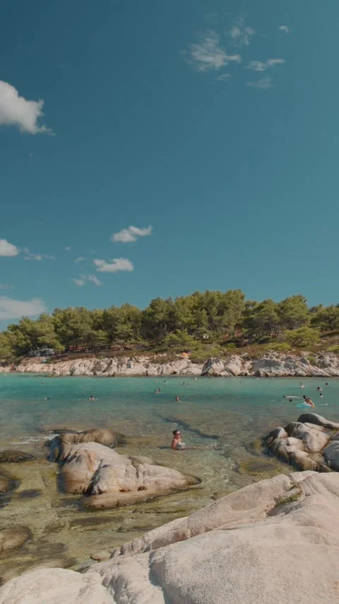 Vertical video Vibrant beach scene showcasing people relaxing on a sandy beach Stock Footage 303698425