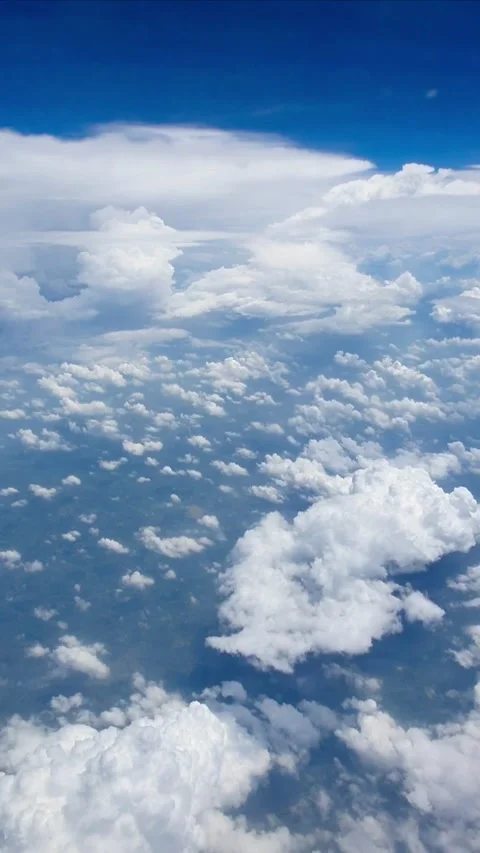Vertical video view from airplane window above soft white clouds and deep blue s Stock Footage 331888163