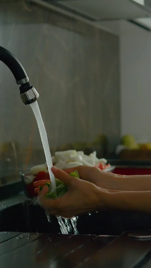 Vertical video Washing fresh basil leaves in the kitchen and preparing a Stock Footage 327578820