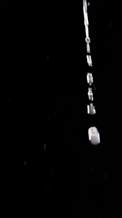 Vertical video. Water Droplets Fall Through an Isolated Black Background, Creati Stock Footage 341413075