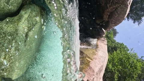 VERTICAL VIDEO, Water flows between the stones forming small waterfalls and Stock Footage 252284056