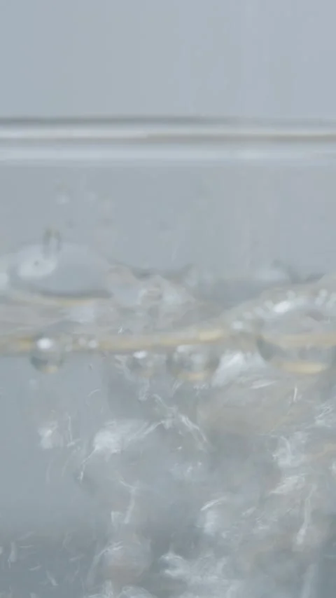 Vertical video Water flows into a glass creating bubbles and splashes Stock Footage 329618683