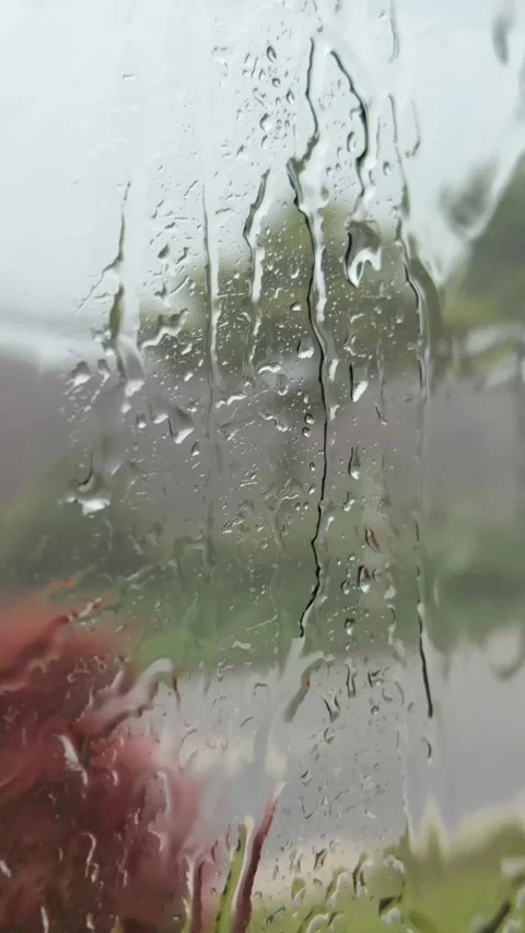 Vertical video of water moving across a bus window during rainfall with a street Stock Footage 338001695