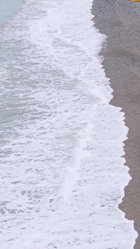 Vertical video of waves breaking along the shore line of Looc Pebble beach Stock Footage 313526592