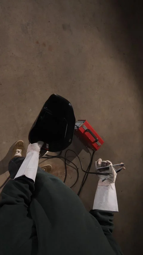 Vertical video welder wearing protective gloves and dark clothing. Holding an Stock Footage 342773870