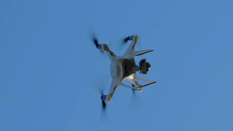 Vertical video. A white quadcopter in flight against a blue sky background. Vídeos de archivo 260463098
