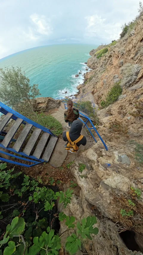 Vertical video. A wide-angle perspective of a man and a woman descending a Stock Footage 294460721